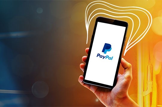 mão segurando um celular com o logo do paypal na tela