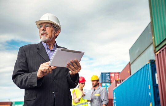 empresário usando um tablet enquanto monitora as atividades em um porto
