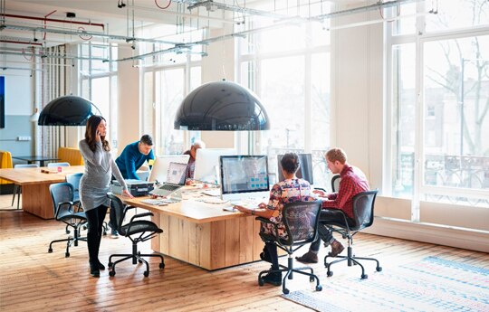 jovens em uma sala com computadores e mesas.