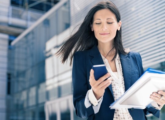 cliente itaú segurando papéis e seu celular no meio da rua