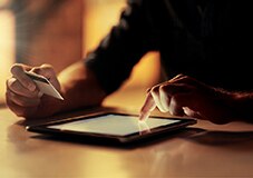 cliente Itaú Personnalité segurando seu cartão com uma mão e mexendo no seu iPad com outra mão aproveitando benefícios do cartão