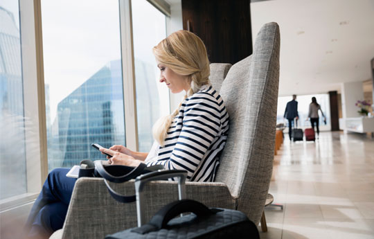 cliente Itaú Private olhando para seu celular dentro da sala VIP de um aeroporto