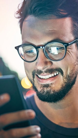 cliente Itaú Uniclass sorrindo e acessado o app Itaú pelo celular