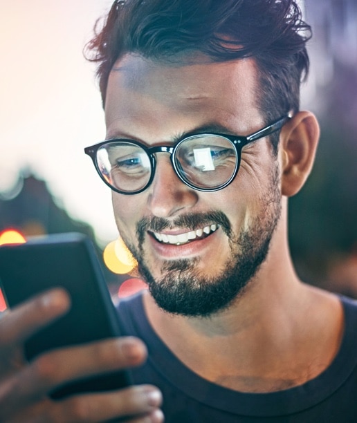 cliente Itaú Uniclass sorrindo e acessado o app Itaú pelo celular