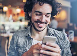 homem sorrindo olhando para o celular