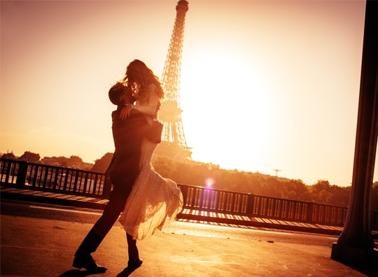 Casal feliz se abraçando em frente a Torre Eiffel