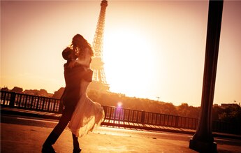 Casal feliz se abraçando em frente a Torre Eiffel
