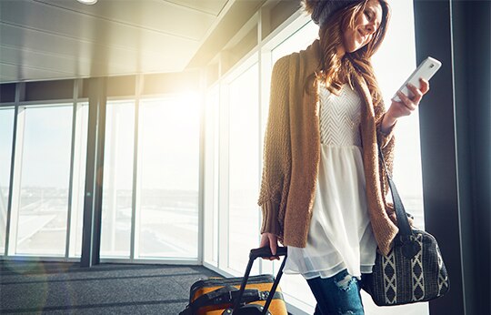 Mulher puxando sua mala de rodinha em uma aeroporto.
