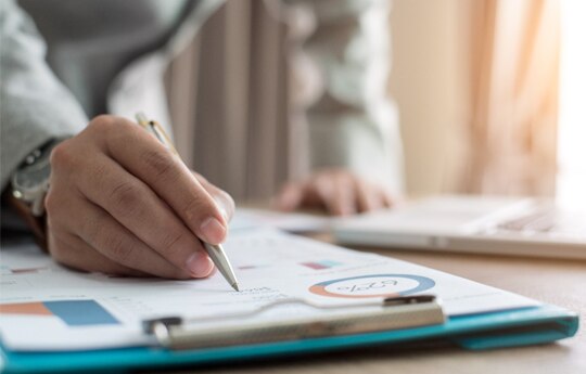 pessoa analisando um relatório na mesa.