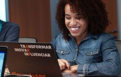 colaboradora do departamento de finanças trabalhando sorridente em frente ao seu notebook.