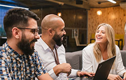 três colaboradores do marketing do Itaú em reunião descontraída.