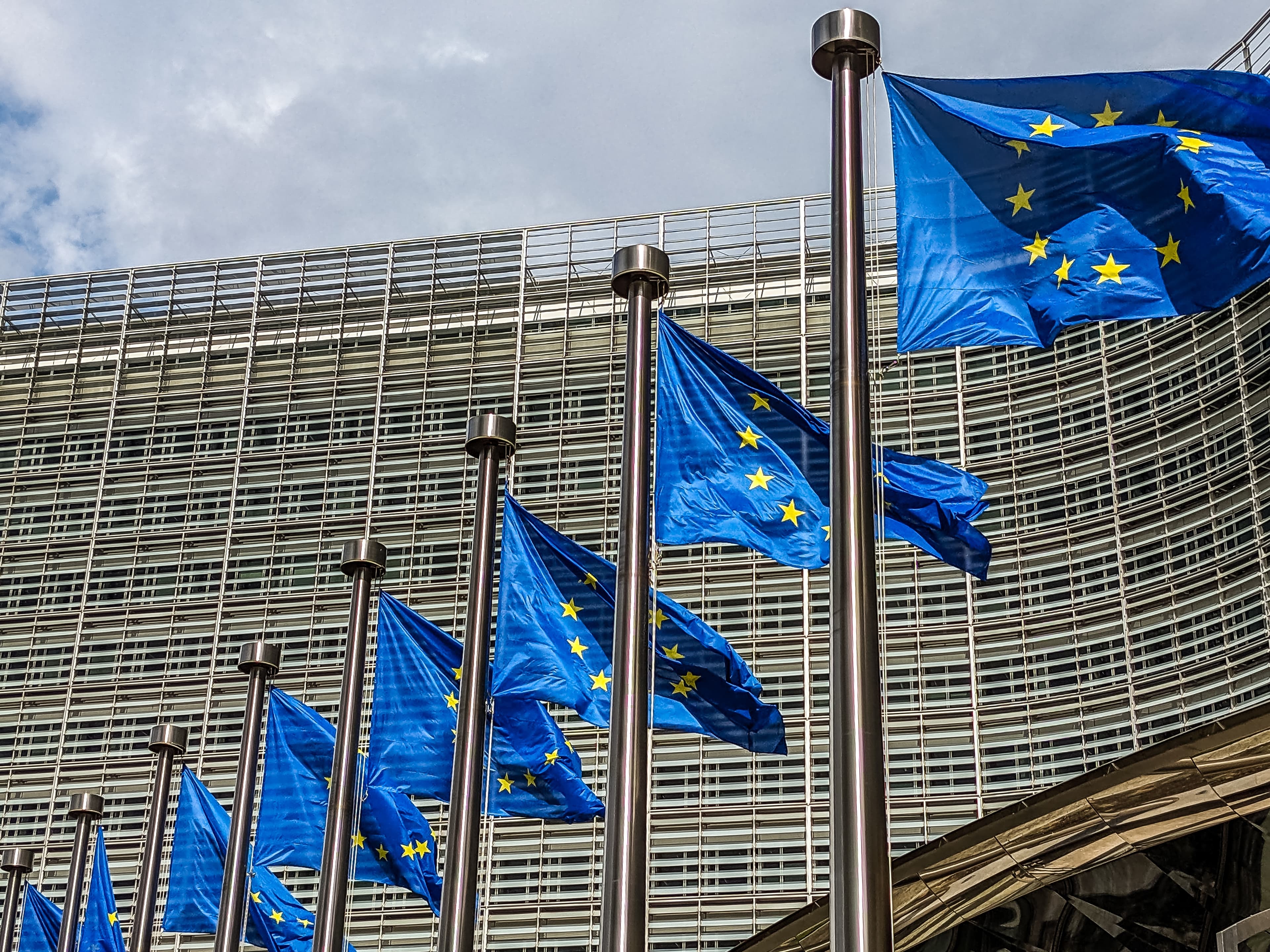 Bandeiras da União Europeia hasteadas em frente à um prédio