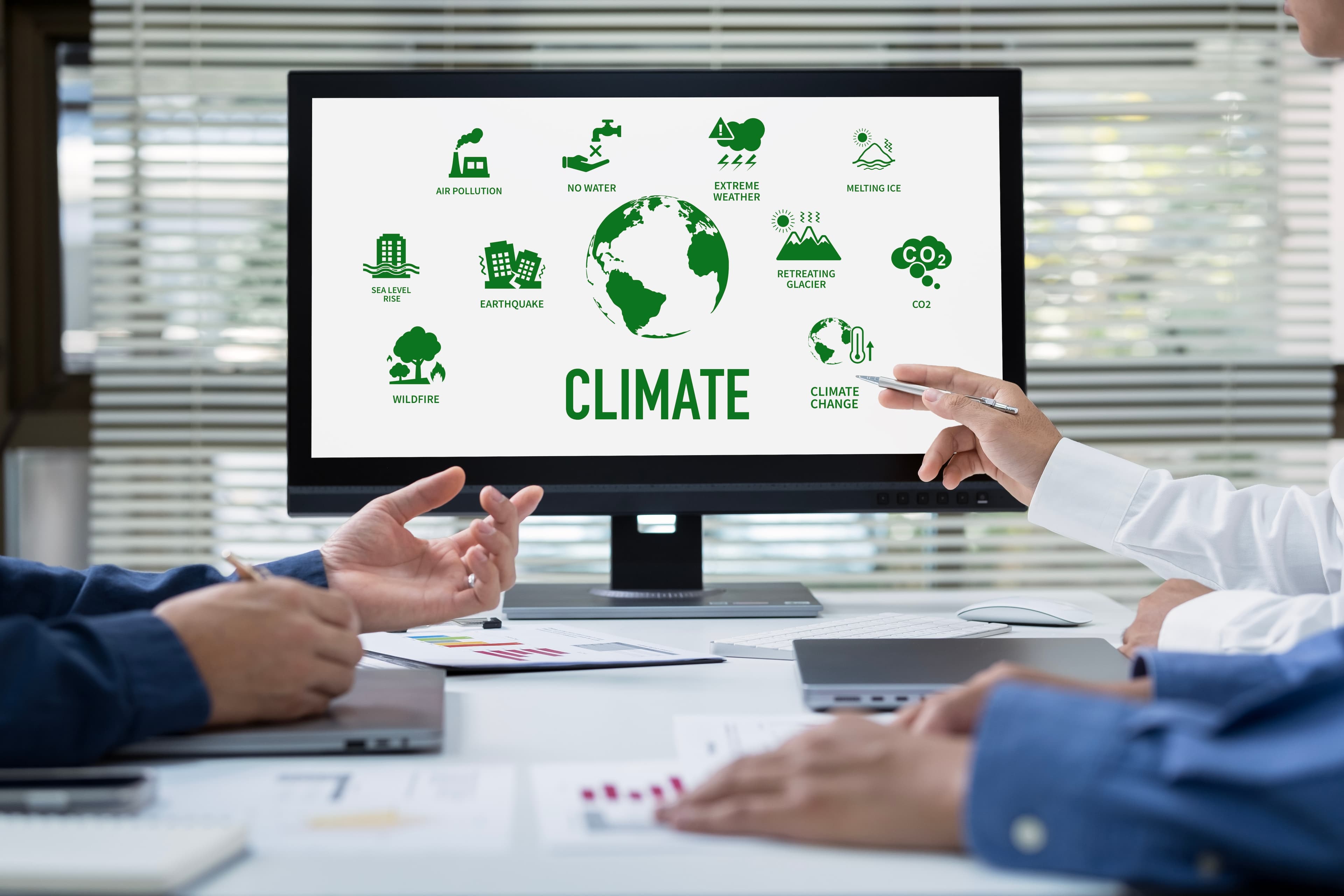 Pessoas apontando para um computador ilustrando símbolos de temas ambientais e sustentáveis