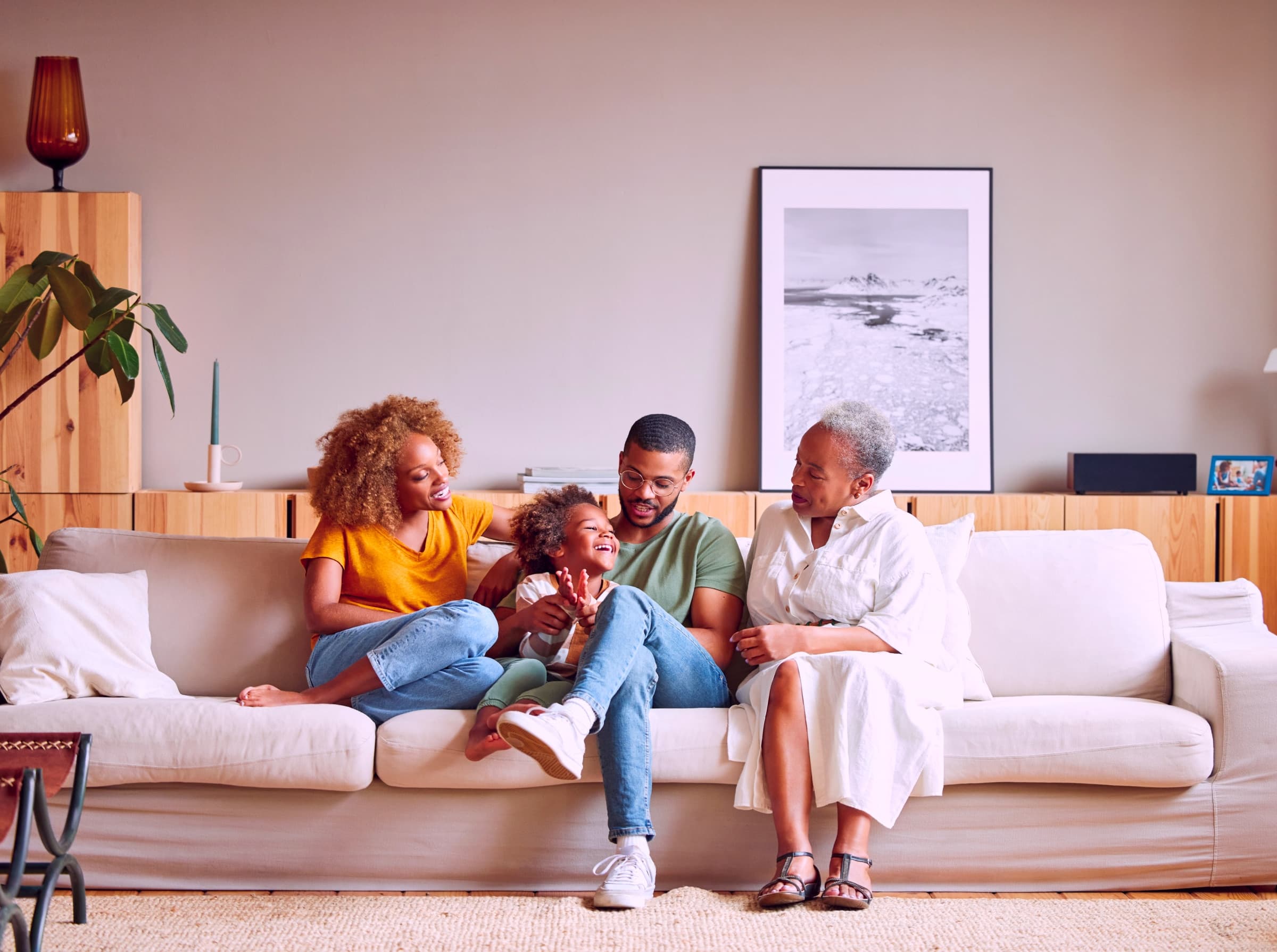 Família em um sofá, com mulher e homem jovens, criança e mulher idosa.