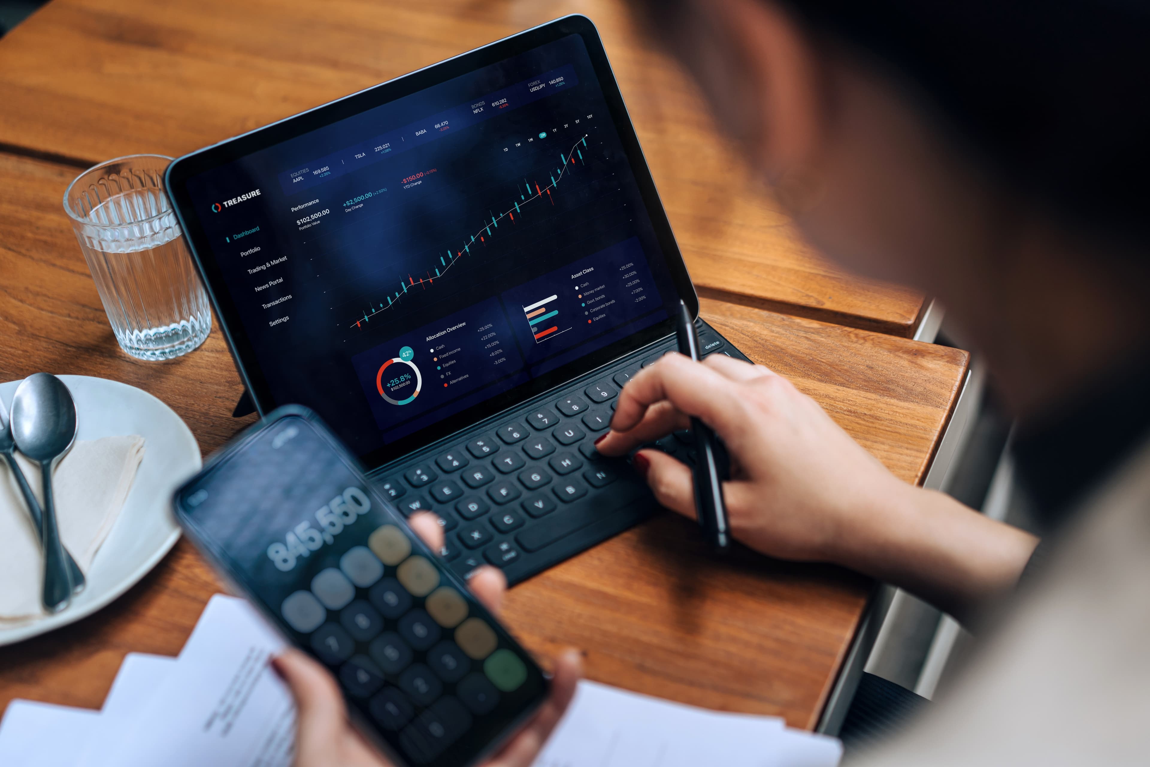 Pessoa conferindo seus investimentos com o apoio do celular e de um tablet. Foto: Getty Images