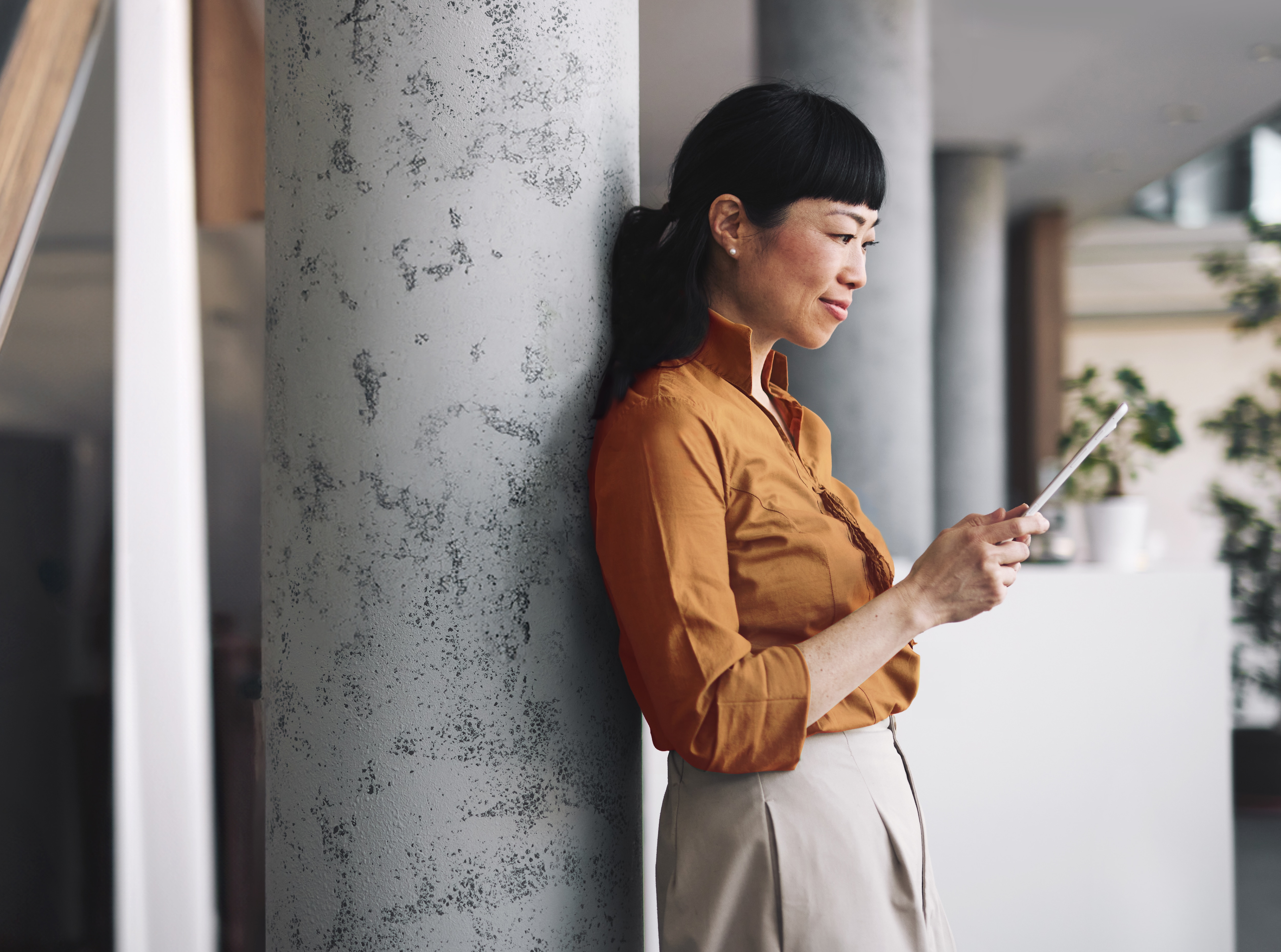 Cliente Itaú Private Bank, mulher em pé segurando um tablet e analisando informações na tela.