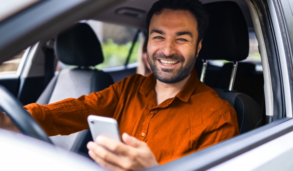 Imagem de um homem dentro do automóvel sorrindo para foto.