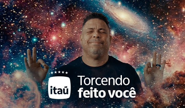 Ronaldo Nazário de peruca, óculos e bandeira no pescoço, todos itens verdes e amarelos. Ao lado, escrito Torcendo Feito Você, com a logo do Itaú