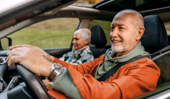 Mulher dirigindo um carro acompanhada de um homem.