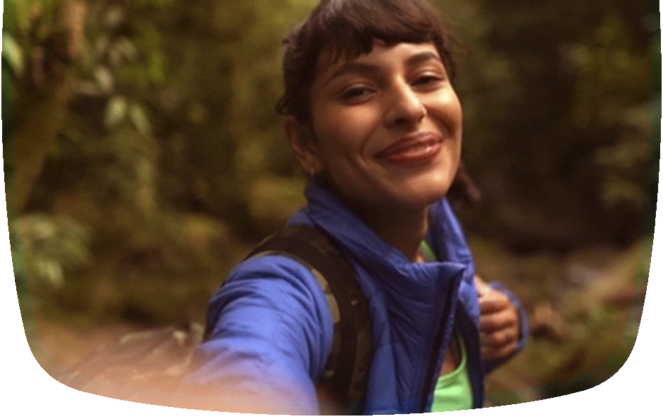 Mulher na natureza se filmando enquanto abre os braços feliz. 