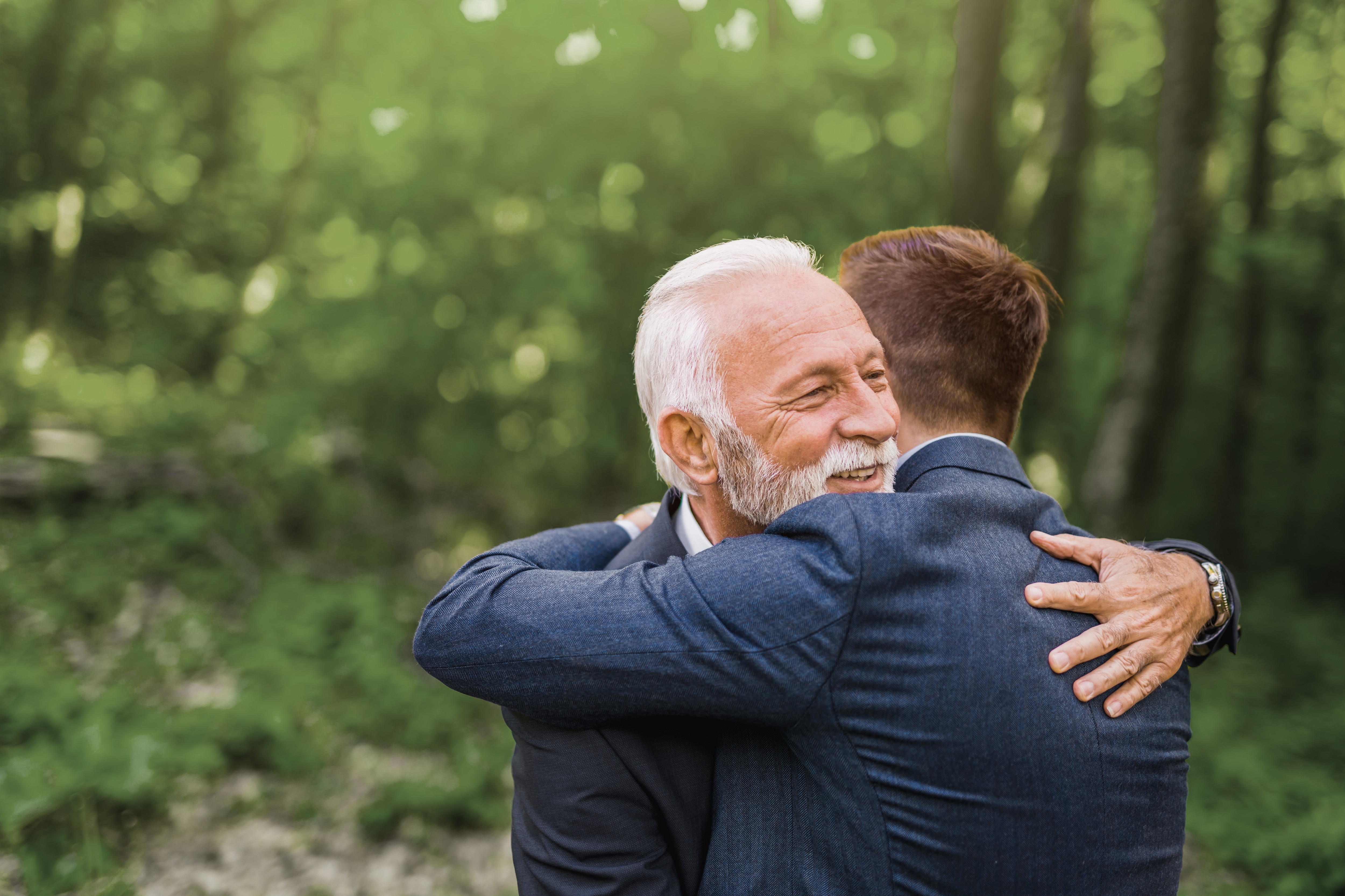 Um homem idoso abraça carinhosamente o filho adulto, clientes Private Bank Inventário.