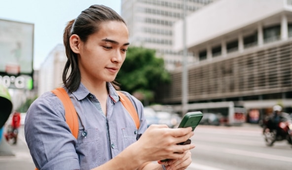 Jovem usando o celular para abrir sua conta Itaú Uniclass e aproveitar o Minhas Vantagens