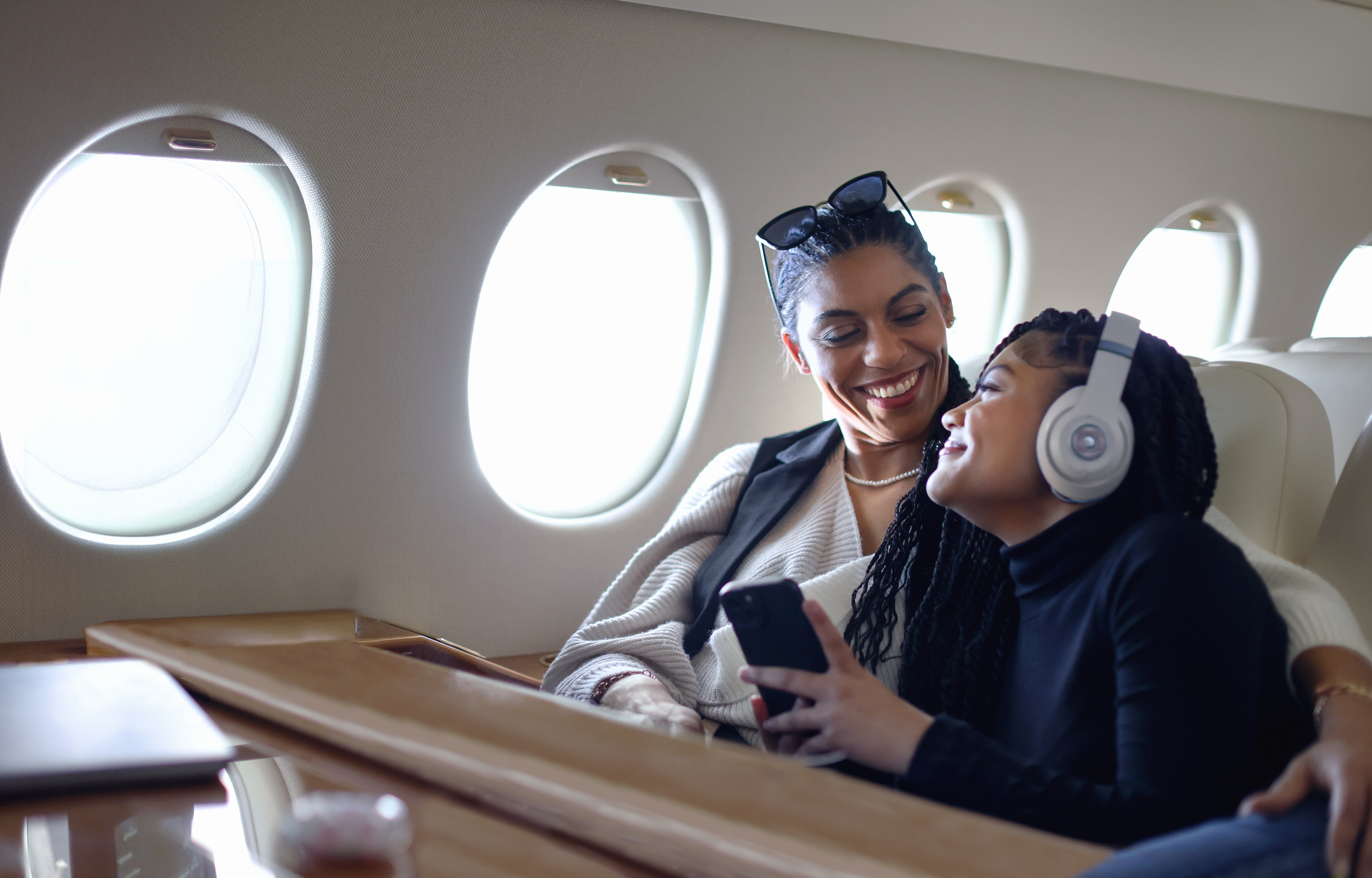 Mulher e menina clientes Itaú Private Bank sorrindo enquanto estão sentadas na poltrona de um avião.