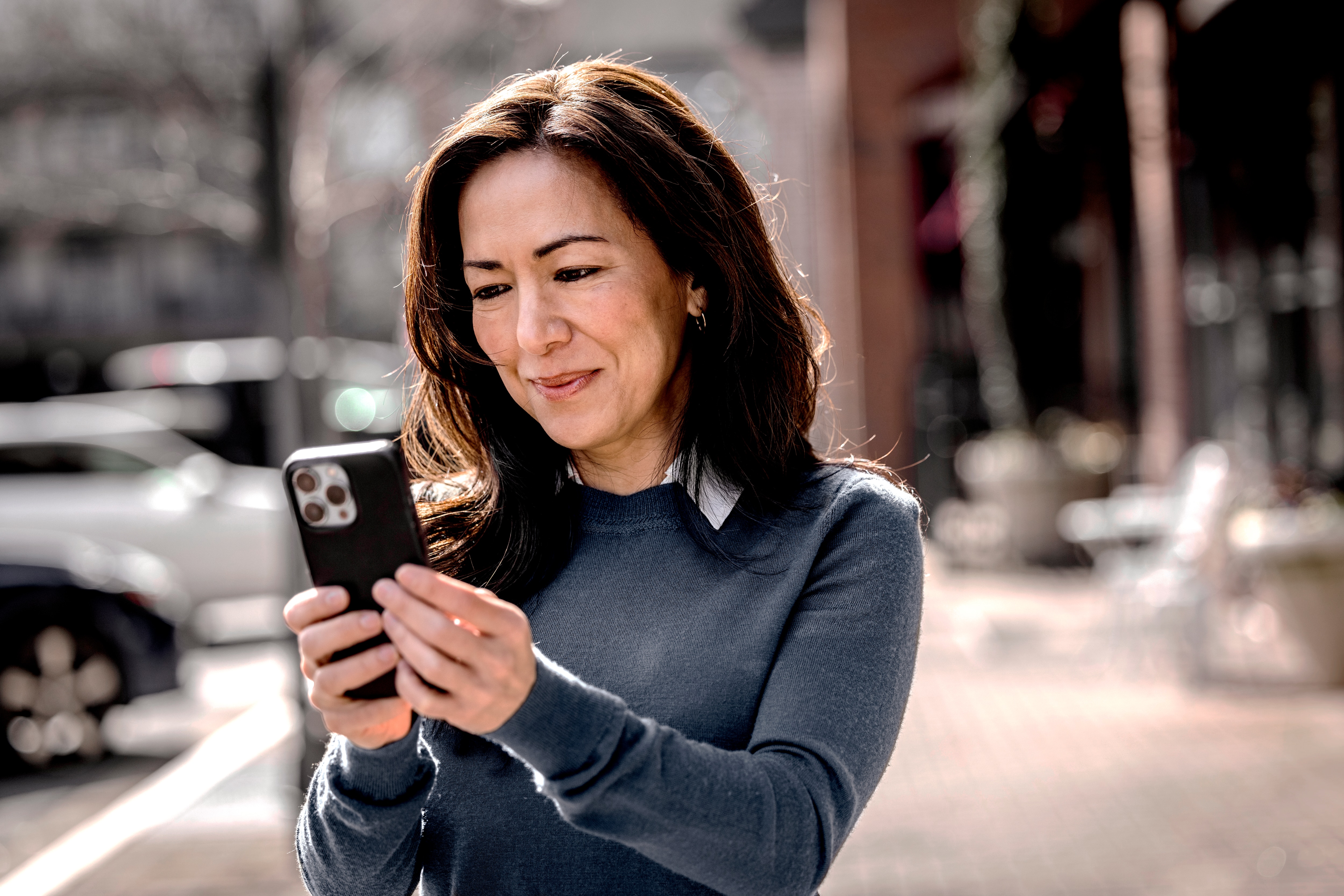 Mulher sorrindo enquanto visualiza tela de celular, cliente de planejamento financeiro para incapacidade civil.