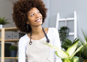 Mulher com avental, sorrindo olhando pro horizonte.