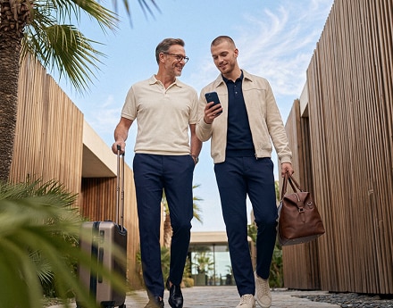 Duas pessoas caminham ao ar livre com malas de viagem.