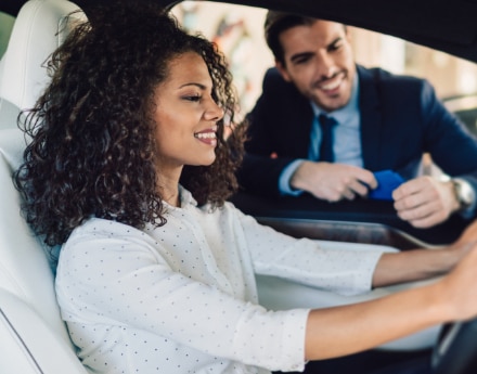 Mulher sentada no carro representando o consórcio Itaú Personnalité