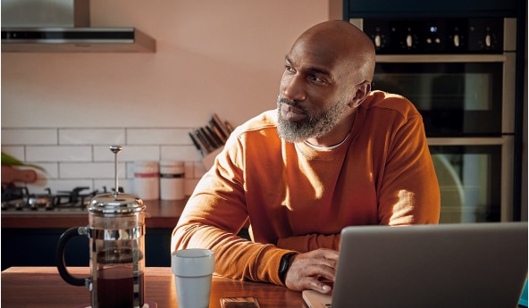 Homem cliente Itaú em frente ao notebook conferindo a Taxa Selic.