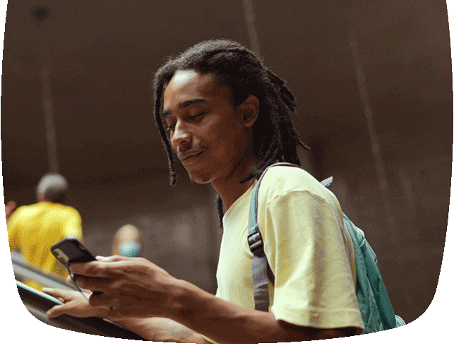 Homem na escada rolante, sorrindo olhando para o celular.
