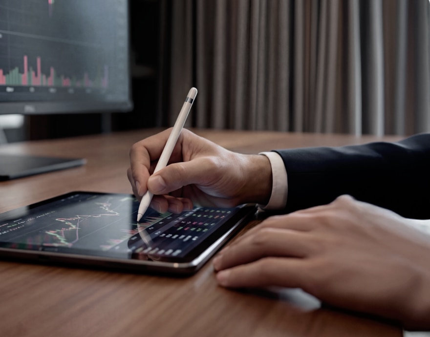 Imagem de mãos utilizando um tablet sobre a mesa.