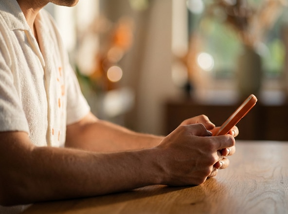 Cliente Itaú mexendo no celular apoiado na mesa