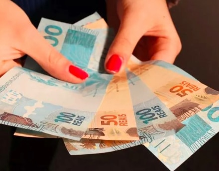 mao de alguem segurando notas de dinheiro