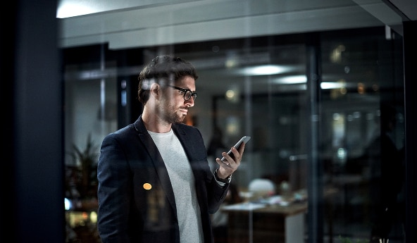 Imagem de um homem de óculos segurando um celular