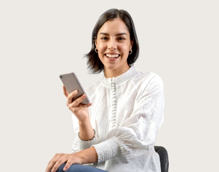 Mulher sentada com o celular na mão sorrindo