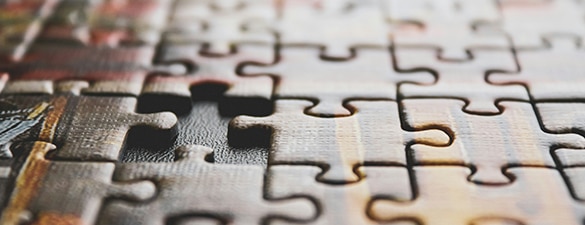 Imagem de um quebra-cabeça com uma única peça pendente sendo colocada