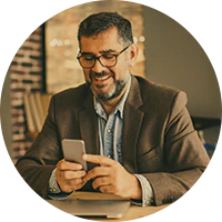 Executivo cliente Itaú Personnalité olhando o smartphone e sorrindo.