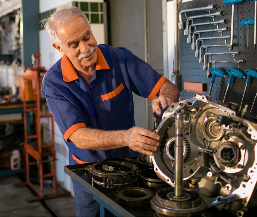 Imagem de um mecânico mexendo em um motor de um carro.