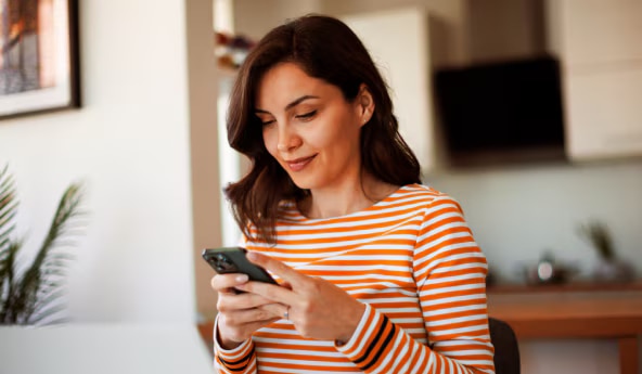 Imagem de uma mulher sorrindo acessando o PIC no seu celular.