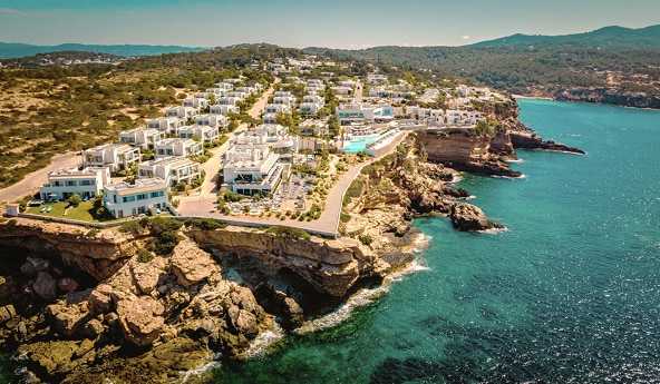 Vista aérea de hotel à beira-mar, cercado por áreas rochosas.