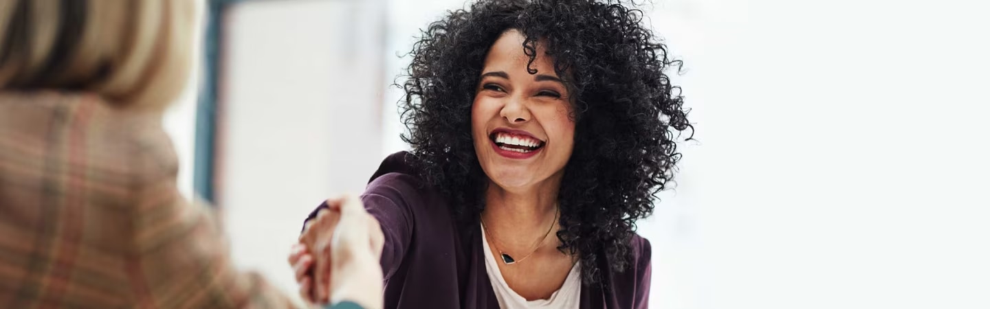 Mulher sorridente apertando a mão de outra mulher