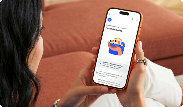 Cliente Itaú Uniclass com seu celular em mãos e o app aberta na tela de Consórcios com Parcela Reduzida.