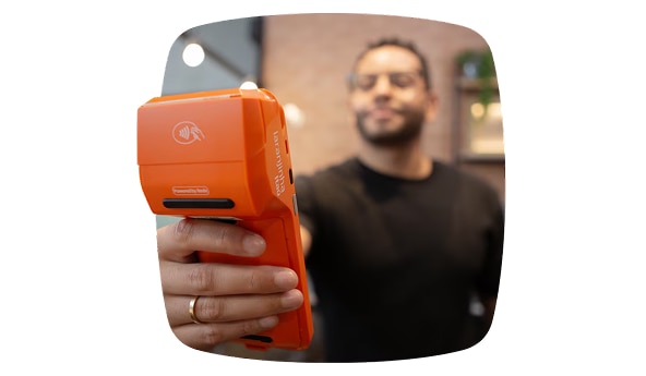 Cliente Itaú Empresas segurando Laranjinha e utilizando o Conversor de moedas