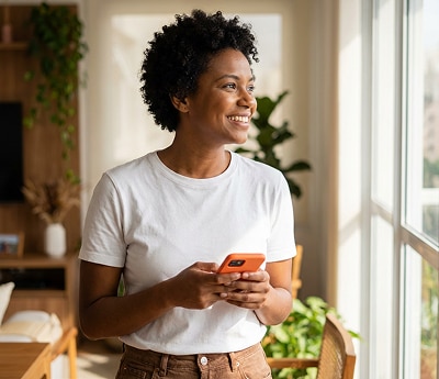 Cliente Itaú olhando para uma janela segurando um celular