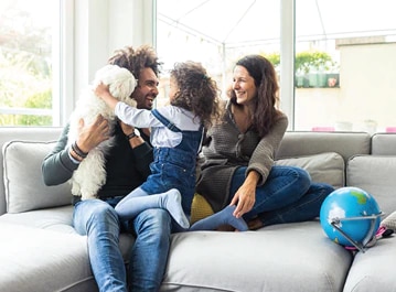 Família com um pai, uma mãe, sua filha e um cachorro brincando.