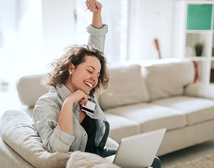 Imagem de uma mulher sentada com um cartão de crédito na mão