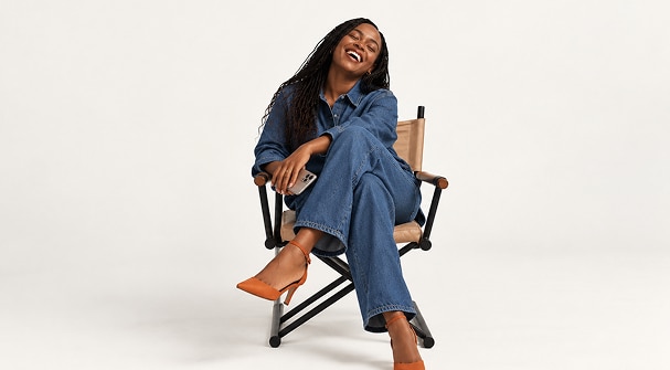 Cliente Itaú Personnalité sentada em uma cadeira de diretora, sorrindo, com pernas cruzadas